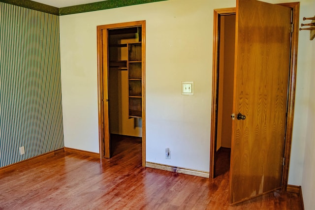 unfurnished bedroom with a spacious closet, a closet, and hardwood / wood-style flooring