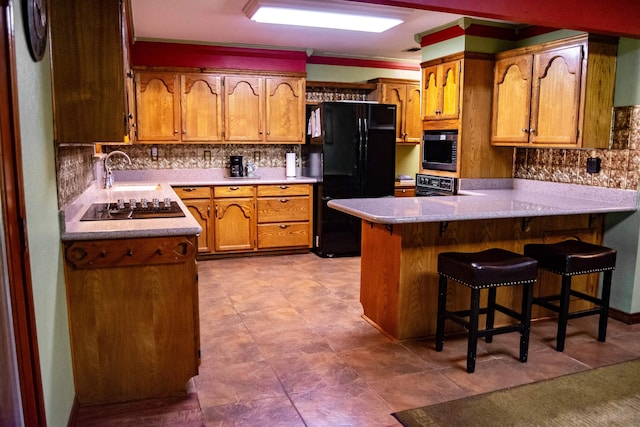 kitchen featuring black appliances, a kitchen bar, kitchen peninsula, and backsplash