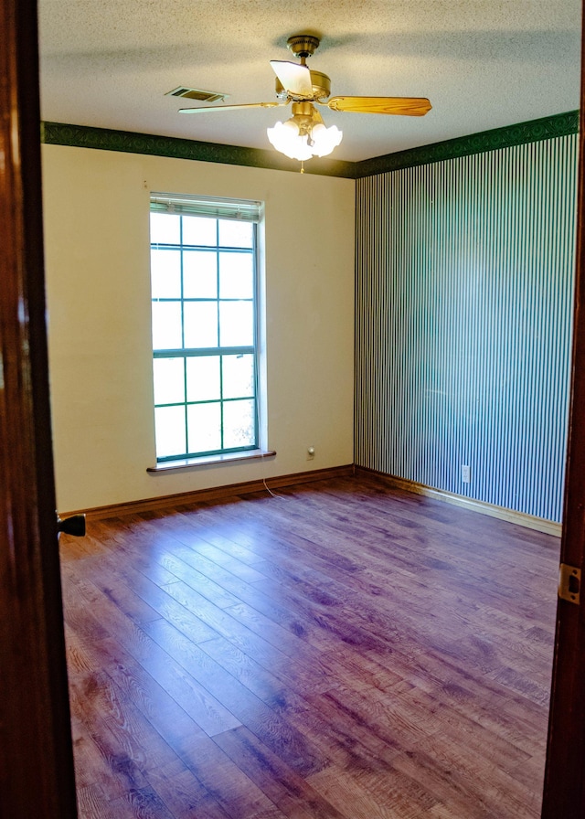 unfurnished room featuring ceiling fan, wood-type flooring, and a textured ceiling