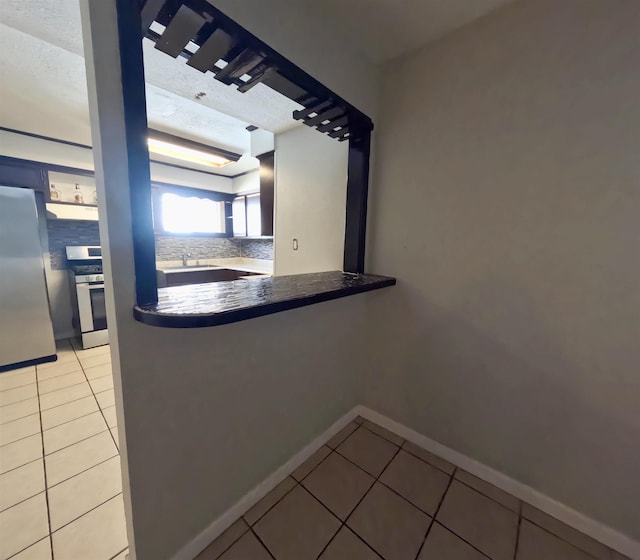 kitchen featuring appliances with stainless steel finishes, sink, decorative backsplash, light tile patterned floors, and a textured ceiling