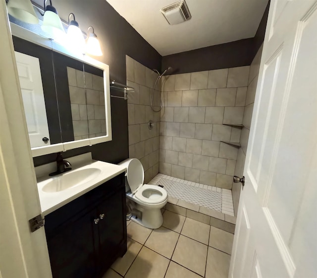 bathroom with tile patterned flooring, vanity, toilet, and tiled shower