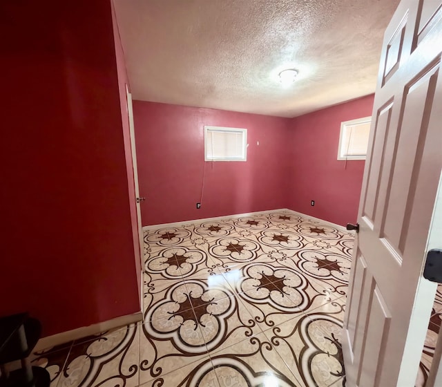 tiled empty room featuring a textured ceiling