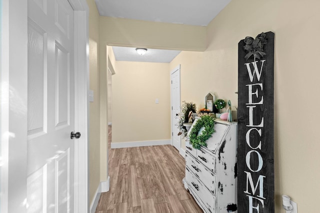 hallway with light wood-style flooring and baseboards