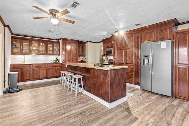 kitchen with a textured ceiling, visible vents, appliances with stainless steel finishes, and light wood-type flooring
