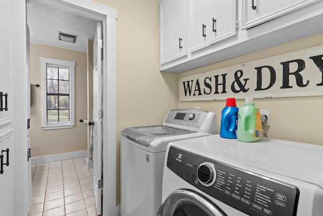 washroom featuring baseboards, light tile patterned floors, cabinet space, and washer and clothes dryer