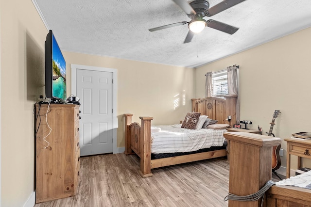 bedroom featuring baseboards, light wood-type flooring, a ceiling fan, and a textured ceiling