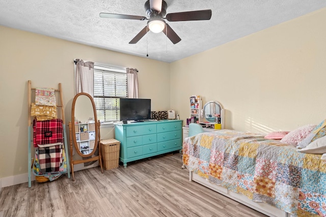 bedroom featuring a ceiling fan, light wood-style floors, and a textured ceiling