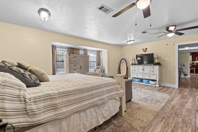 bedroom with visible vents, wood finished floors, a ceiling fan, and a textured ceiling