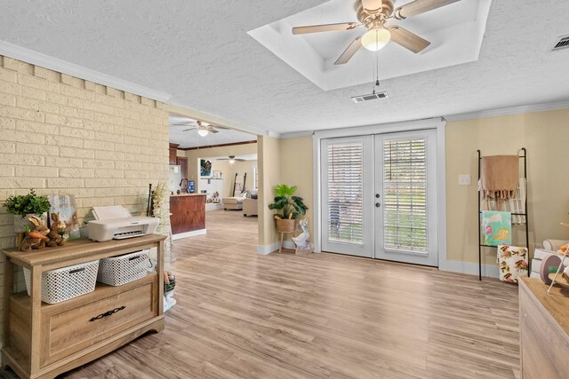 interior space with a textured ceiling, visible vents, a ceiling fan, and ornamental molding
