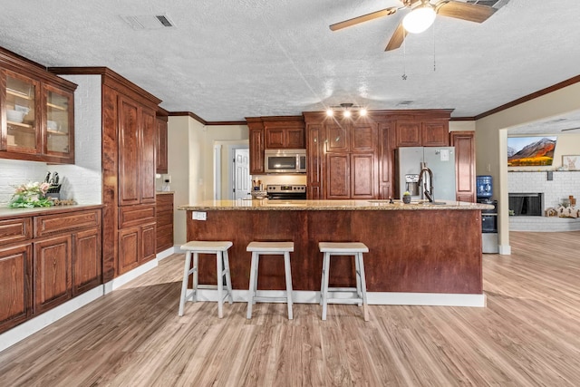 kitchen featuring ceiling fan, visible vents, light wood-style flooring, a textured ceiling, and appliances with stainless steel finishes