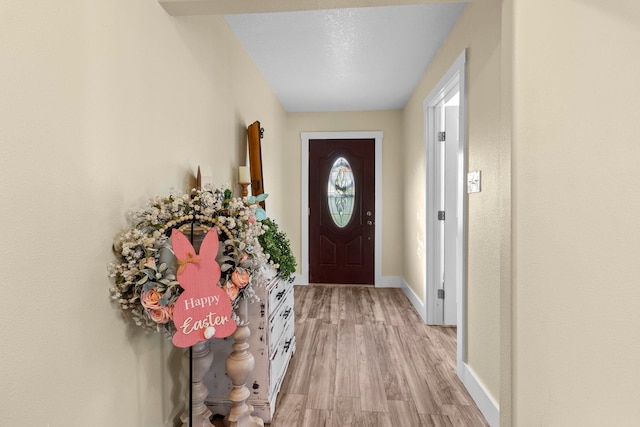 doorway to outside featuring light wood finished floors and baseboards