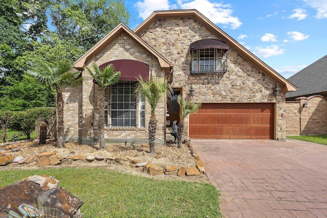 french country inspired facade with stone siding, a garage, and decorative driveway