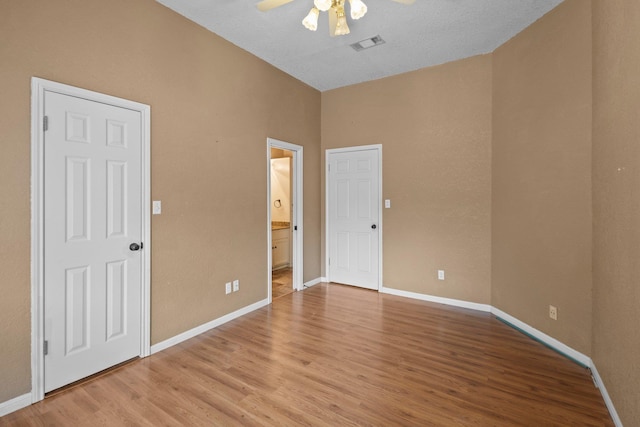 unfurnished bedroom with light wood-style floors, connected bathroom, and baseboards