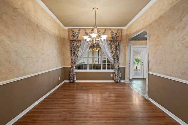 unfurnished dining area with healthy amount of natural light, a chandelier, crown molding, wood finished floors, and baseboards