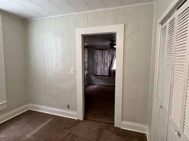 hallway featuring carpet and wood walls