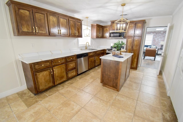 kitchen with appliances with stainless steel finishes, a center island, sink, hanging light fixtures, and ornamental molding