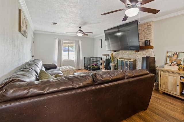 living room with hardwood / wood-style flooring, a textured ceiling, crown molding, and a brick fireplace