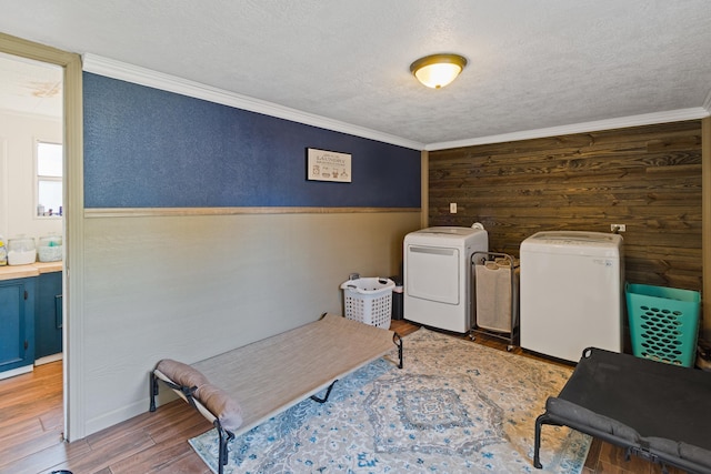 clothes washing area with a textured ceiling, wood walls, independent washer and dryer, and ornamental molding