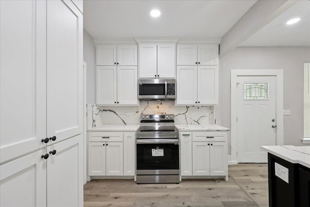 2033 Broadway St, Beaumont, TX 77702 - kitchen featuring appliances with stainless steel finishes, backsplash, light wood finished floors, white cabinetry, and recessed lighting