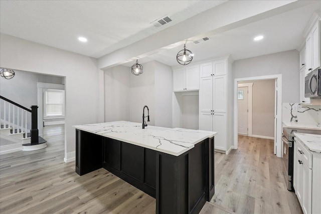 2033 Broadway St, Beaumont, TX 77702 - kitchen featuring stainless steel appliances, white cabinets, light wood-type flooring, and recessed lighting