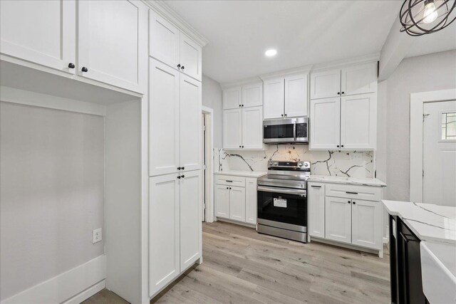 2033 Broadway St, Beaumont, TX 77702 - kitchen with stainless steel appliances, white cabinets, light wood-style flooring, tasteful backsplash, and recessed lighting
