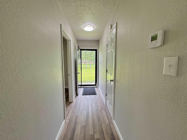 13595 Rolling Hills Dr, Beaumont, TX 77713 - hall featuring wood finished floors, a textured wall, baseboards, and a textured ceiling