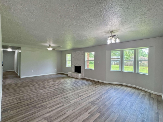 13595 Rolling Hills Dr, Beaumont, TX 77713 - unfurnished living room featuring wood finished floors, a textured ceiling, baseboards, ceiling fan, and a brick fireplace