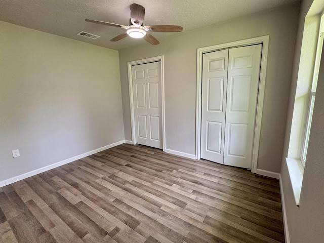13595 Rolling Hills Dr, Beaumont, TX 77713 - unfurnished bedroom with wood finished floors, baseboards, a textured ceiling, a ceiling fan, and two closets