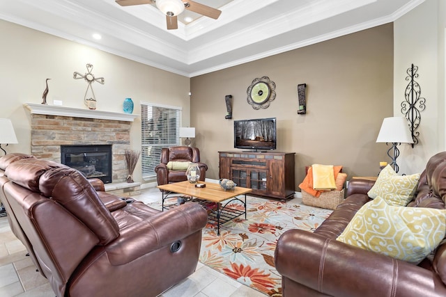 tiled living room with a tray ceiling, ceiling fan, a fireplace, and ornamental molding