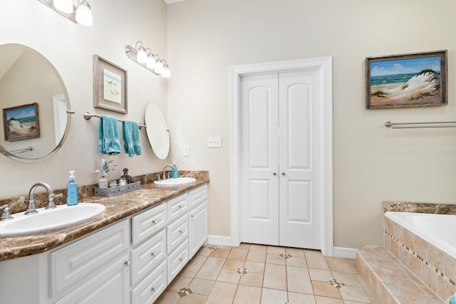 bathroom with tile patterned flooring, vanity, and a relaxing tiled tub