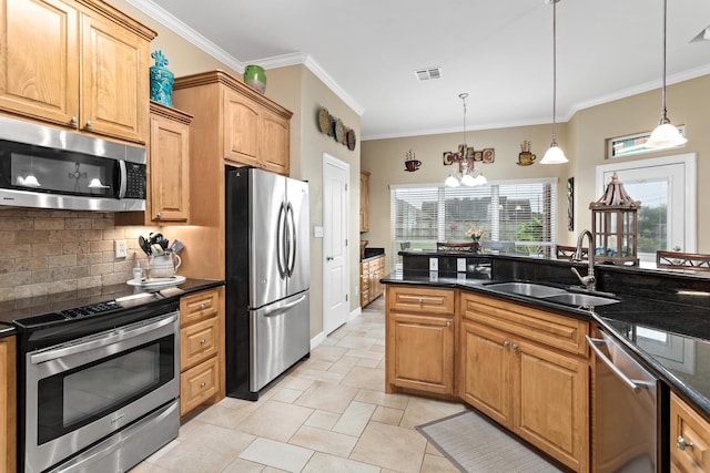 kitchen with sink, decorative light fixtures, dark stone countertops, appliances with stainless steel finishes, and a notable chandelier