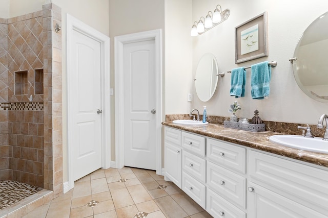 bathroom with tile patterned flooring, vanity, and tiled shower