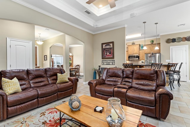 tiled living room featuring a tray ceiling, ceiling fan, sink, and ornamental molding