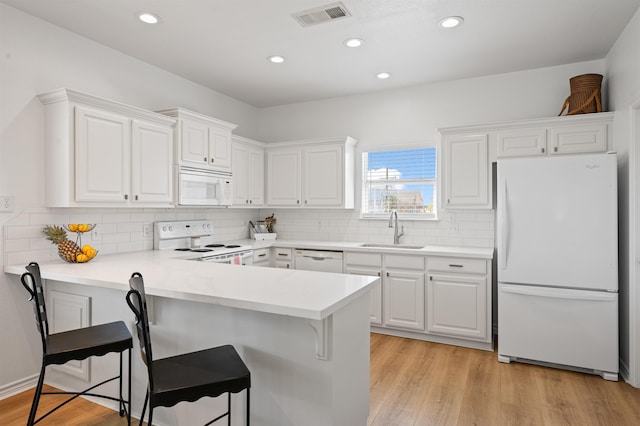 981 S S Gtwy, Crystal Beach, TX 77650 - kitchen with white appliances, a sink, a breakfast bar area, white cabinetry, and a peninsula