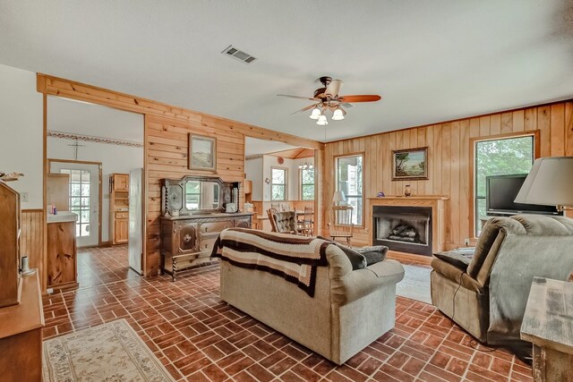 living room with ceiling fan and wooden walls