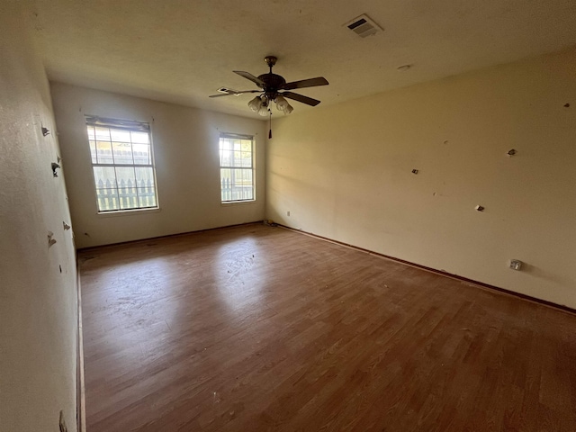 spare room with wood finished floors, a ceiling fan, and baseboards