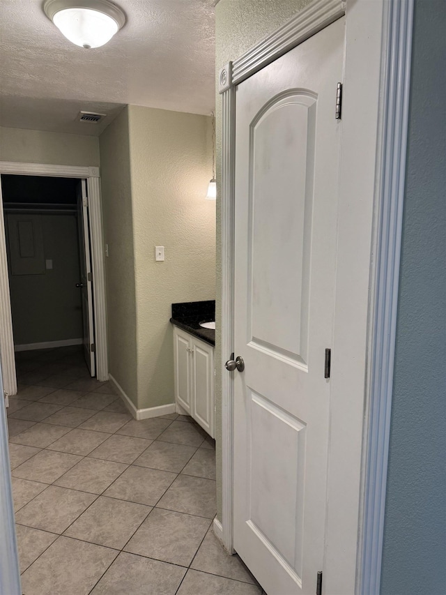 bathroom with visible vents, vanity, a textured wall, tile patterned floors, and a textured ceiling