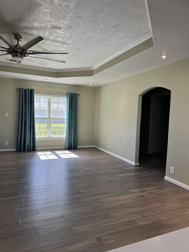 empty room featuring baseboards, dark wood-style floors, arched walkways, a textured ceiling, and a raised ceiling