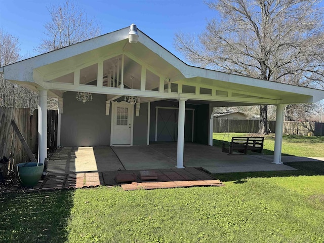 rear view of house with a patio area, a lawn, a carport, and fence