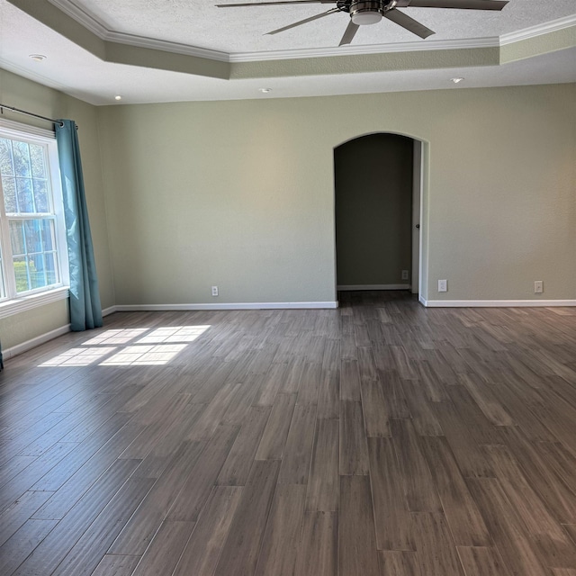 spare room featuring ornamental molding, arched walkways, a textured ceiling, a raised ceiling, and dark wood-style flooring