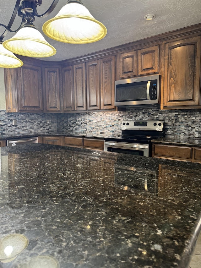 kitchen featuring dark stone countertops, backsplash, and stainless steel appliances