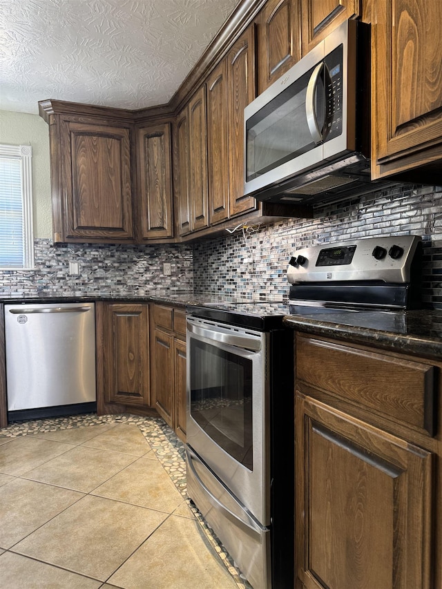 kitchen featuring decorative backsplash, light tile patterned floors, and appliances with stainless steel finishes