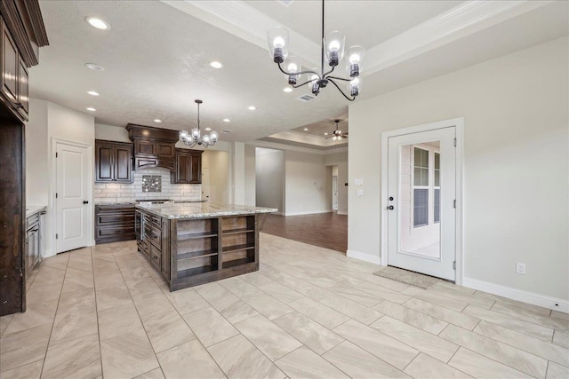 kitchen with decorative light fixtures, a chandelier, a center island, a raised ceiling, and dark brown cabinets