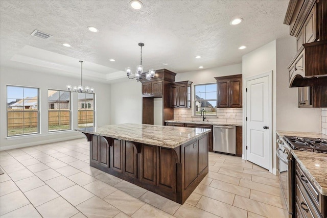 kitchen with appliances with stainless steel finishes, a kitchen breakfast bar, light stone countertops, and a kitchen island