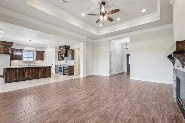 unfurnished living room with a raised ceiling, crown molding, a fireplace, and light hardwood / wood-style floors