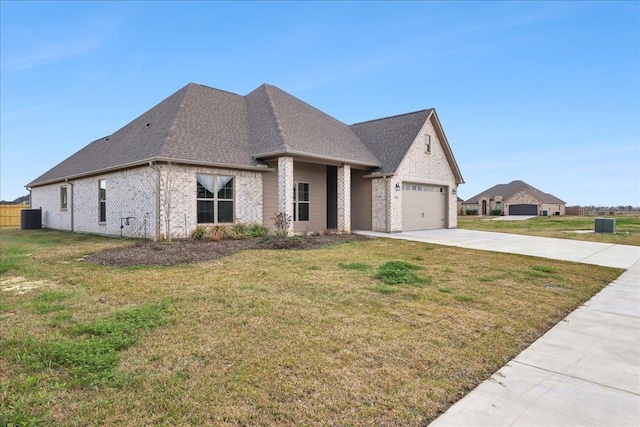 french country style house featuring a garage, a front lawn, and central air condition unit