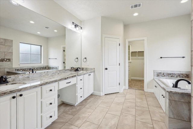 bathroom with vanity and tiled bath