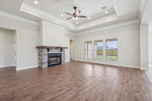 unfurnished living room featuring hardwood / wood-style flooring, a fireplace, a tray ceiling, and ceiling fan