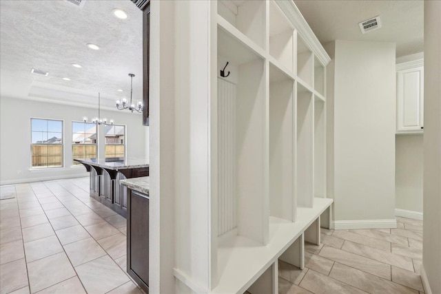 mudroom featuring light tile patterned flooring, a chandelier, and a textured ceiling