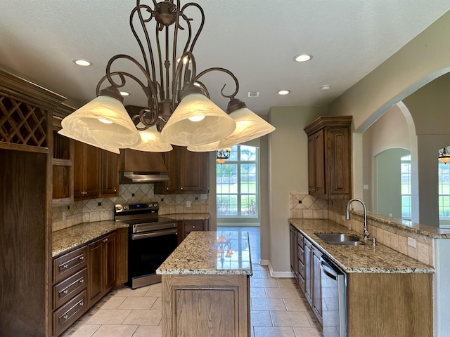 305 Tyler Dr, Bridge City, TX 77630 - kitchen with stainless steel appliances, a sink, arched walkways, tasteful backsplash, and light stone counters